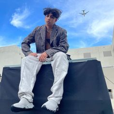 a man sitting on top of a black tarp with an airplane in the background