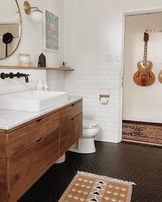 a bathroom with a sink, toilet and guitar on the wall above it's mirror