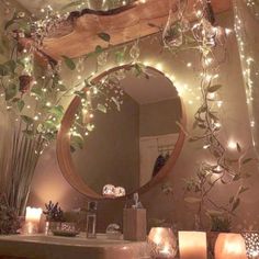 a bathroom decorated with candles and greenery in front of a mirror that has lights on it