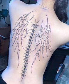 the back of a woman's upper body with tattoos on her ribs and wings