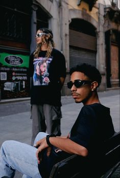 a man sitting on top of a bench next to a woman in black shirt and jeans