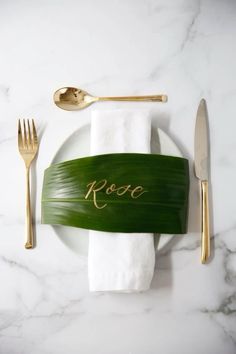 a white plate topped with a knife and fork next to a green leaf covered napkin