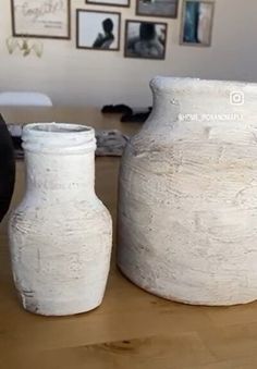 two white vases sitting on top of a wooden table