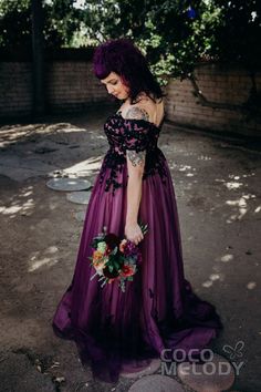 a woman in a long purple dress holding a bouquet and looking down at the ground