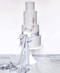 a three tiered cake with flowers and ribbons