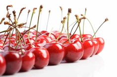 a group of cherries sitting on top of each other with stems sticking out of them