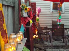 there are many jars with candles on the outside table and in front of the house