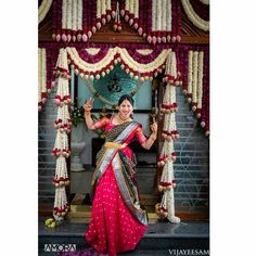 a woman in a pink and gold sari posing for the camera with her hands up