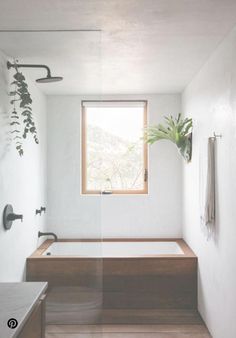 a bathroom with a tub, sink and window in the corner that has plants growing on it