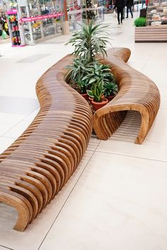 a wooden bench sitting on top of a tiled floor next to a potted plant