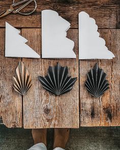 three pieces of paper cut out to look like seashells on a wooden table