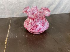 a pink glass vase sitting on top of a wooden table