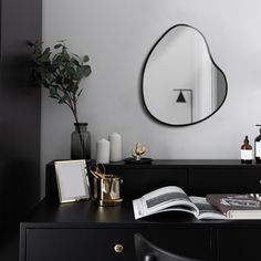 a black dresser topped with a mirror next to a vase filled with flowers