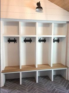 an empty room with several white shelves and hooks on the wall, along with gray herringbone tile flooring