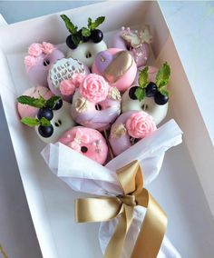 a box filled with pink and white donuts covered in frosting, blackberries and blueberries