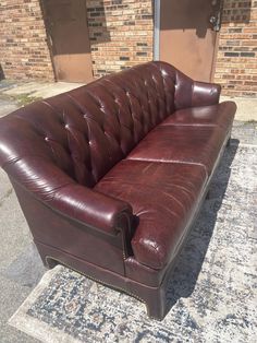 a brown leather couch sitting on top of a carpeted floor next to a brick building