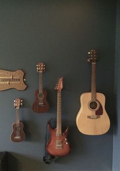 three guitars are hanging on the wall next to each other in a room with blue walls