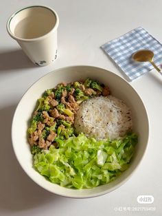 a white bowl filled with rice, meat and vegetables next to a cup of coffee