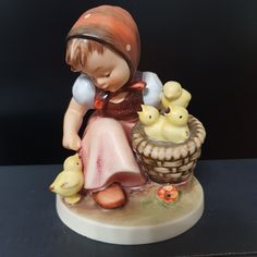 a figurine of a girl with ducks in a basket