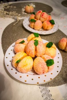 small pastries are on plates with green leaves and sprinkled powdered sugar