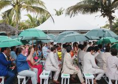 a group of people sitting under umbrellas in the rain at an outdoor event or gathering