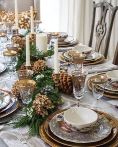 the table is set for christmas dinner with pine cones and candles