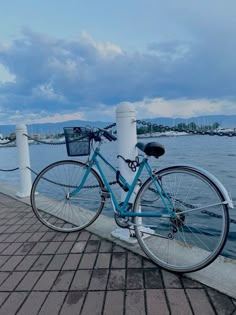 a blue bike parked next to a white pole on the side of a body of water