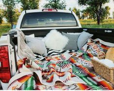 the back end of a pickup truck with blankets and pillows on it's bed