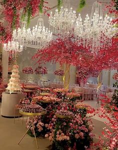 a room filled with lots of pink flowers and chandeliers hanging from the ceiling