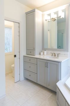 a large bathroom with two sinks, mirrors and cabinets in the middle of the room