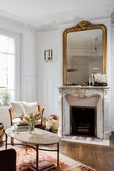 a living room filled with furniture and a fire place in front of a mirror on the wall