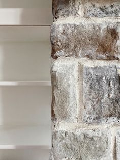 a brick wall with white shelves in front of it