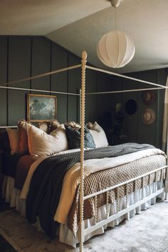 a bedroom with a four poster bed and two lamps hanging from the ceiling above it