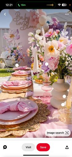 a table set with pink plates and flowers