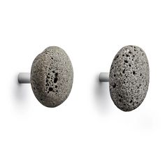 two gray rocks sitting on top of a white wall next to each other in the shape of balls