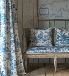 a blue and white couch sitting in front of a window next to a wooden wall