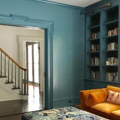 a living room filled with furniture and bookshelves next to a doorway that leads to a hallway