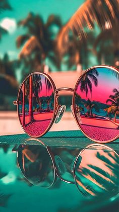 a pair of sunglasses with palm trees reflected in them