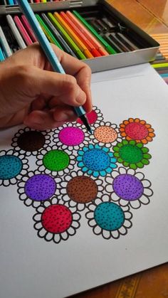 a person is drawing with colored pencils on paper