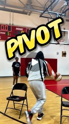 a young man is playing basketball in a gym with two other people watching from the sidelines