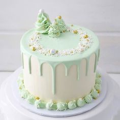 a green and white frosted cake with trees on top