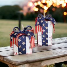 two wrapped gift boxes sitting on top of a wooden table with fireworks in the background