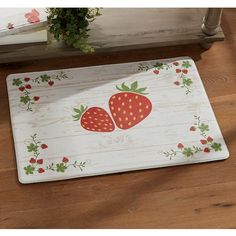 a door mat with two strawberries painted on the front and back of it, sitting on a wooden floor