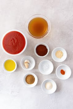 several bowls with different types of sauces and seasonings in them on a white surface