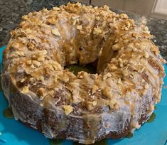 a frosted donut with walnuts on top sitting on a blue platter