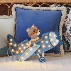 a toy airplane with lights on it sitting on a pillow in front of a bed