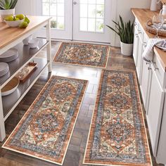 three rugs in the middle of a kitchen with fruit on the counter and plates