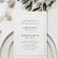 the wedding stationery is laid out on a plate with greenery and ribbons around it