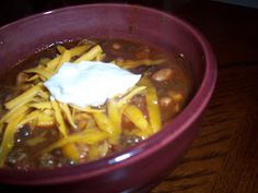 a purple bowl filled with chili and cheese