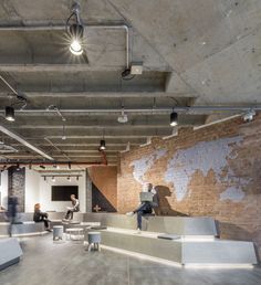 people sitting at tables in an office with exposed brick walls and floor to ceiling windows